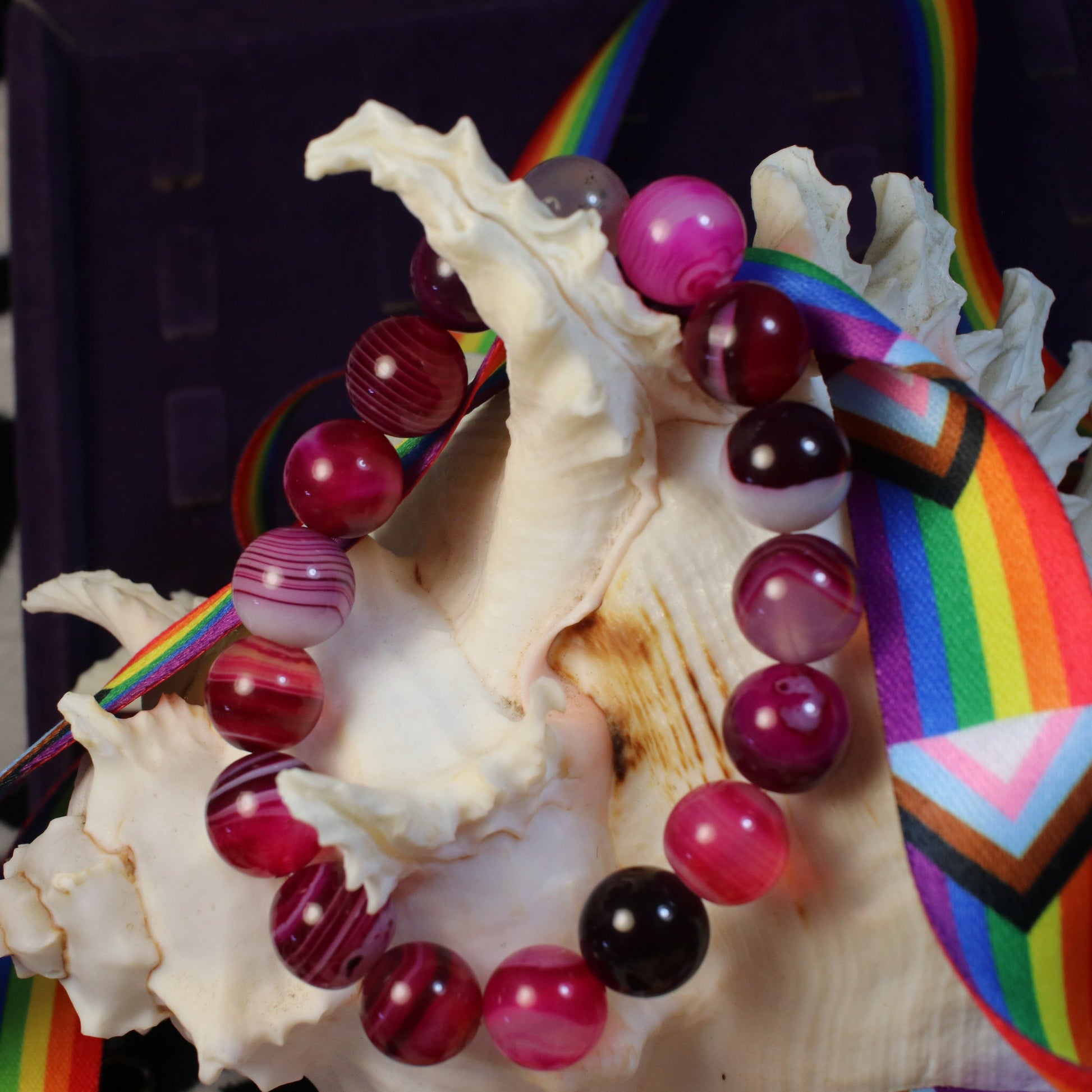 Beaded bracelet with rainbow charm on a seashell against a zebra-patterned background