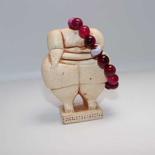 Decorative item with a beige figure and red beads on a white background