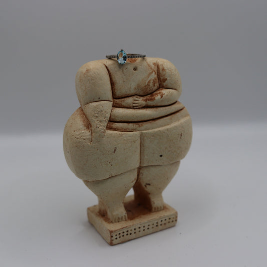 Ceramic sculpture of a stylized human figure on a gray background